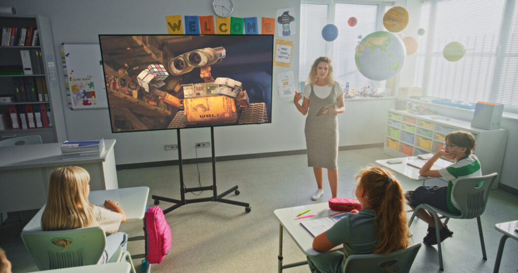Female Teacher Educating Elementary School Students. Large Digital Screen with Chroma Key Mock Up